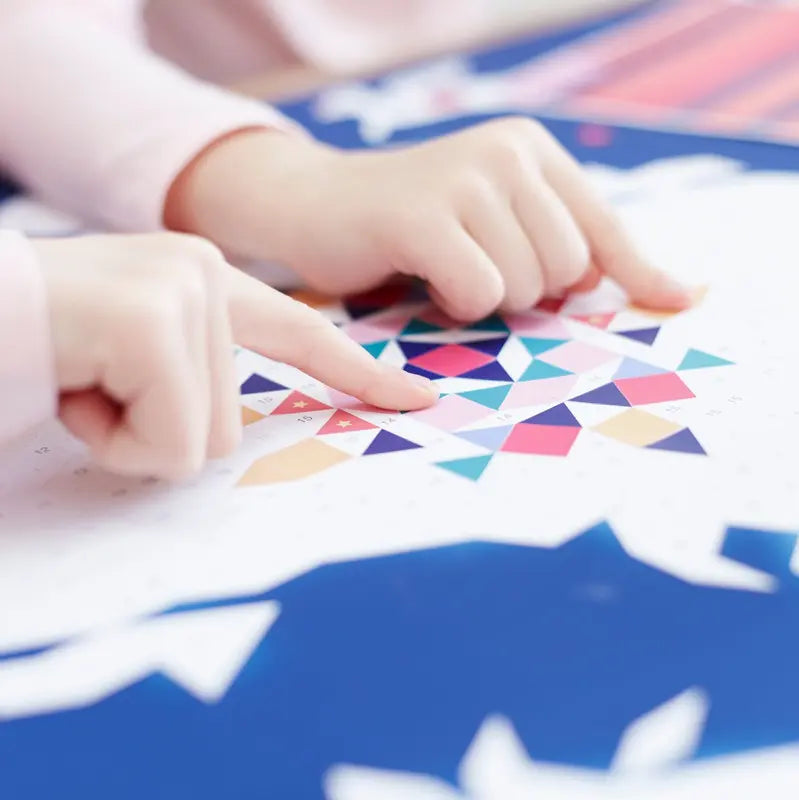 Two hands arrange geometric stickers onto the Poppik Creative Sticker Poster – Constellation, forming a star-inspired mosaic. Blue and pink shapes in the background enhance the pixel art vibe of this creative sticker activity.