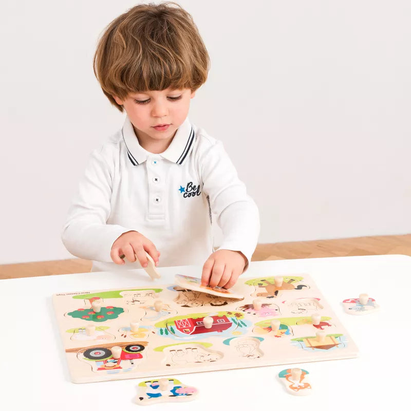A young boy playing with the New Classic Toys Peg Puzzle Farm.