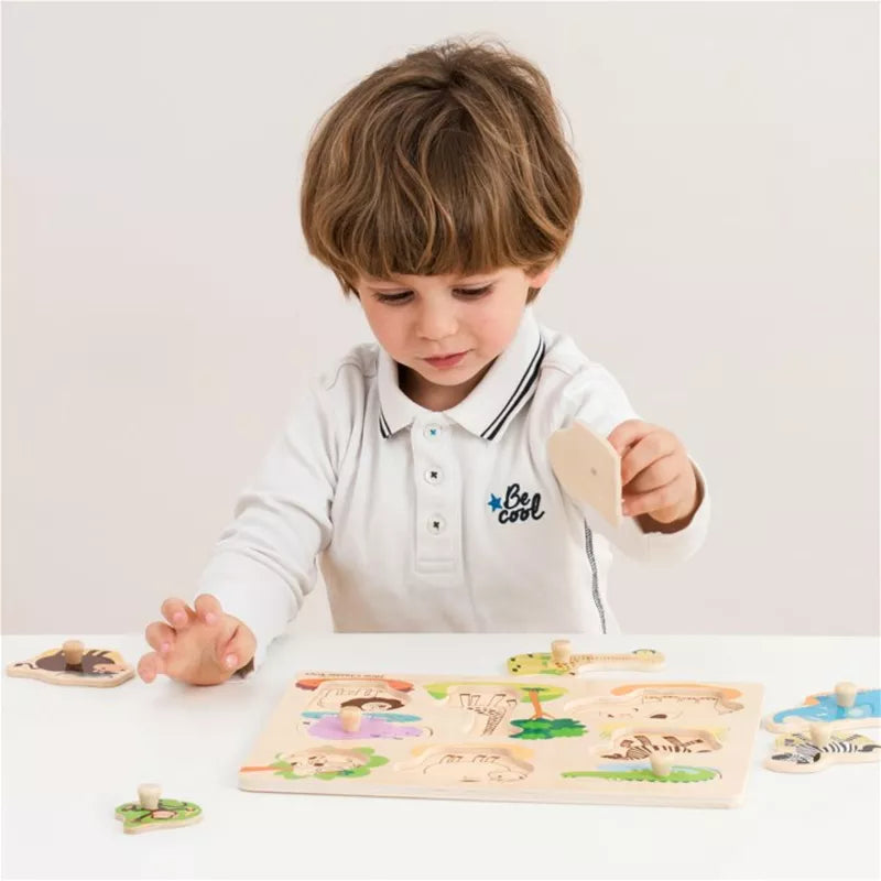 A young boy playing with a New Classic Toys Peg Puzzle - Safari - 8 pieces.