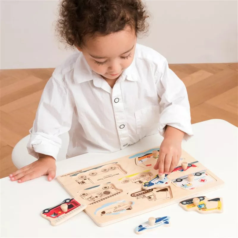 A little girl playing with a New Classic Toys Peg Puzzle - Transport - 8 pieces.