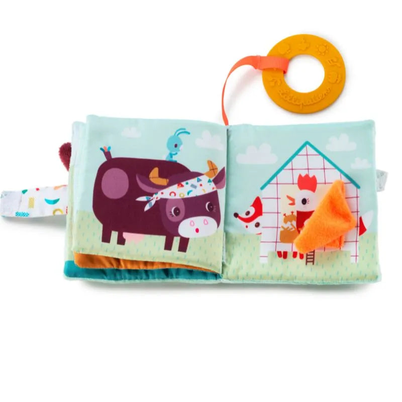 The Lilliputiens I'm Discovering Playbook Farm is a charming cloth baby book, ideal as a baby's first toy or gift. It features a cartoon cow and chicken in a barn setting, complete with an attached teething ring on an orange strap for convenience.