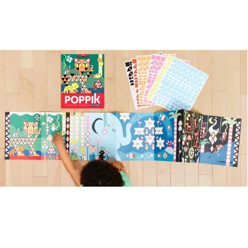 A child arranges colorful repositionable stickers from the Poppik Creative Stickers Jungle set on a large illustrated jungle-themed poster, with sticker sheets and the Poppik box nearby on a wooden floor.