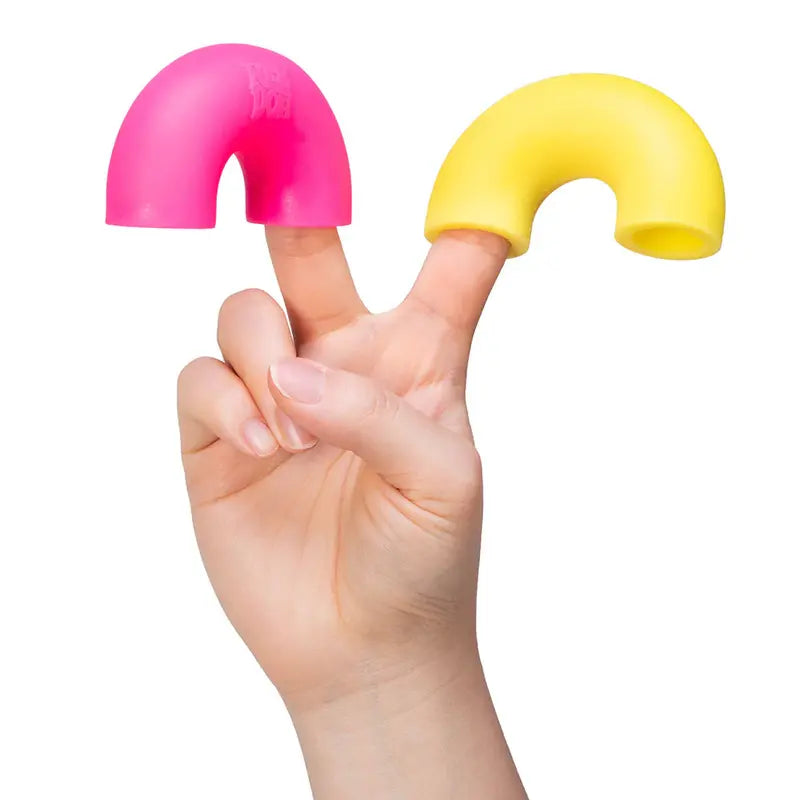 A hand raises two fingers, each capped with a hollow, U-shaped Mac and Squeeze NeeDoh fidget toy—one pink, one yellow—against a white background.
