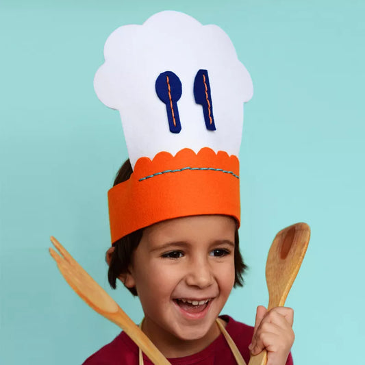 a young boy wearing a Cook Chef Sewing Kit and holding wooden spoons.