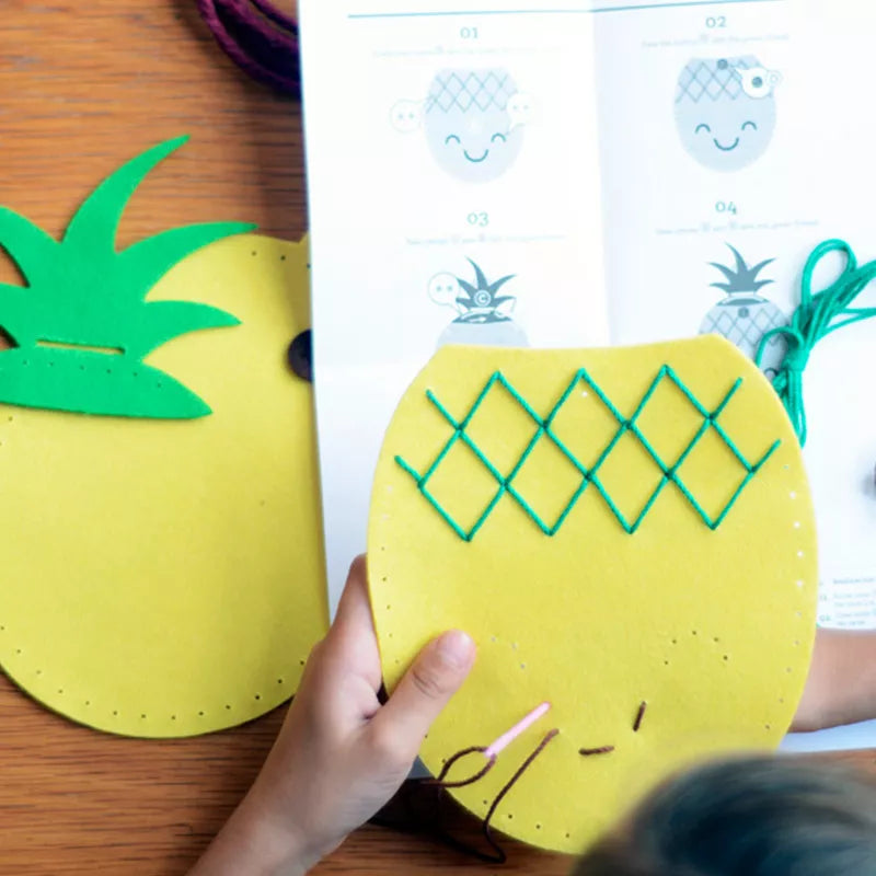 A child is using the Bag Sewing Kit Pineapple to make a paper pineapple craft.