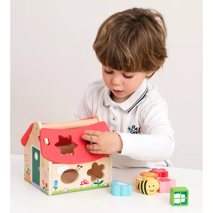 A young boy playing with a New Classic Toys Shape Sorting House.