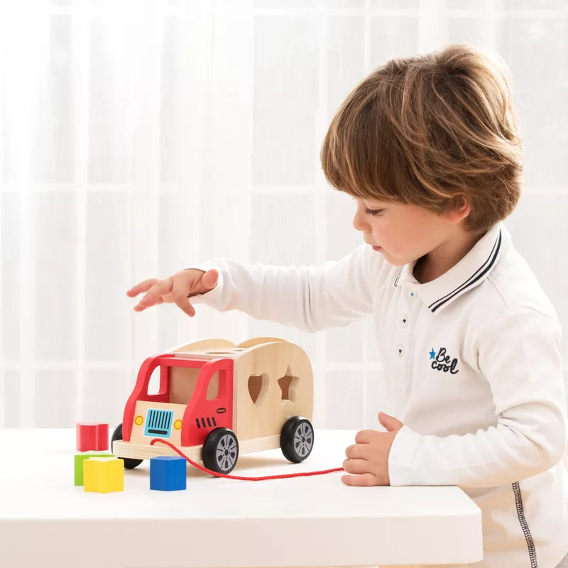 A young boy playing with a New Classic Toys Shape Sorting Truck.