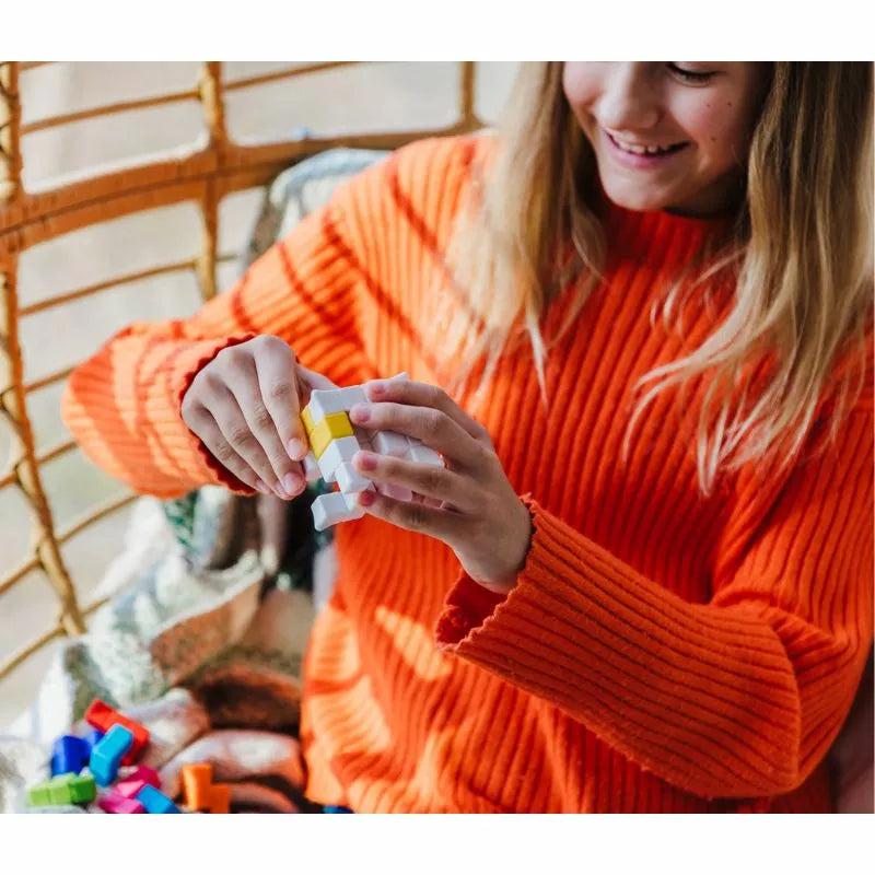 A girl in an orange sweater is playing with the SmartGames Plug & Play Puzzler.