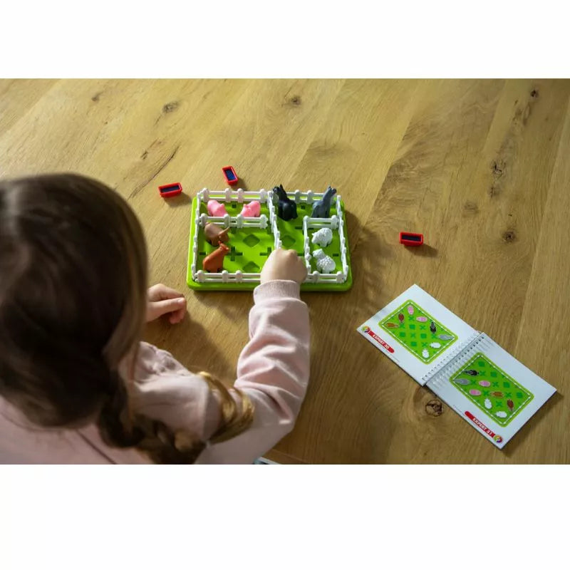 A little girl playing with the SmartGames Smart Farmer on a wooden table.