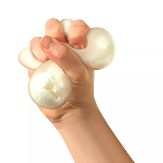 A human hand squeezing a Snow Ball Crunch Needoh, made from non-toxic materials, showing deformation from the grip, against a white background.