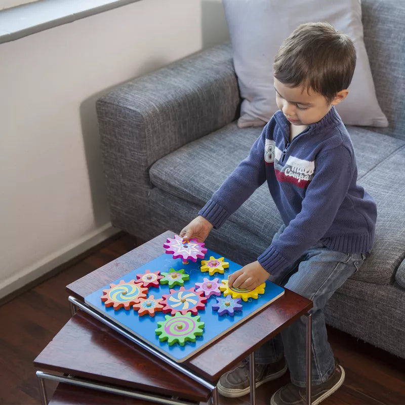 A young boy playing with the New Classic Toys Spinning Gear Puzzle on a table.