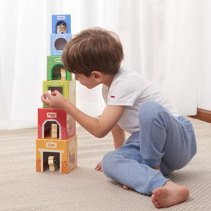 A little boy playing with New Classic Toys Stacking Cubes with 6 Farm Friends.