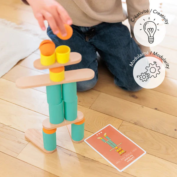 Child playing with a colorful Stix Construction Creative Cards stacking toy following instructions on a card.