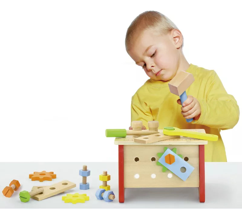 A young boy playing with the New Classic Toys Table Top Workbench.
