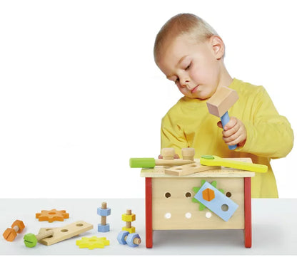 A young boy playing with the New Classic Toys Table Top Workbench.