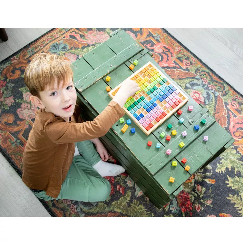 A young boy exploring maths with the New Classic Toys Times Table Tray on a rug.