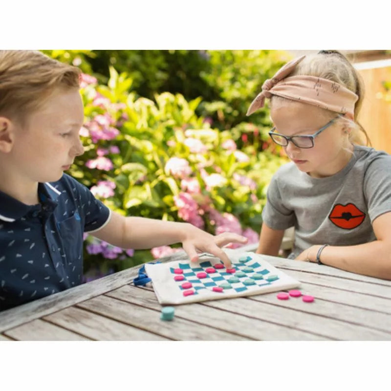 A boy and a girl playing a game of Buitenspeel Travel Draughts & Tic Tac Toe.