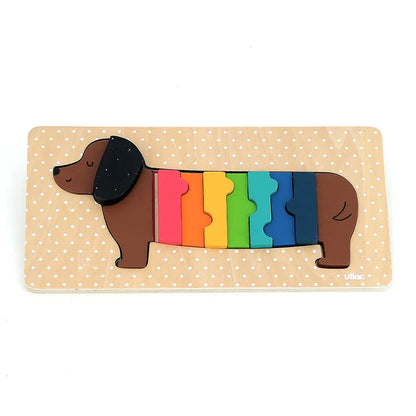 The Vilac Dog Wooden Puzzle is a delightful jigsaw puzzle featuring a dachshund set against a dotted beige background. Perfect for ages 1 year and up, this charming puzzle consists of seven colorful pieces forming the dog's body, with colors arranged from front to back in red, pink, yellow, green, light blue, dark blue, and brown.