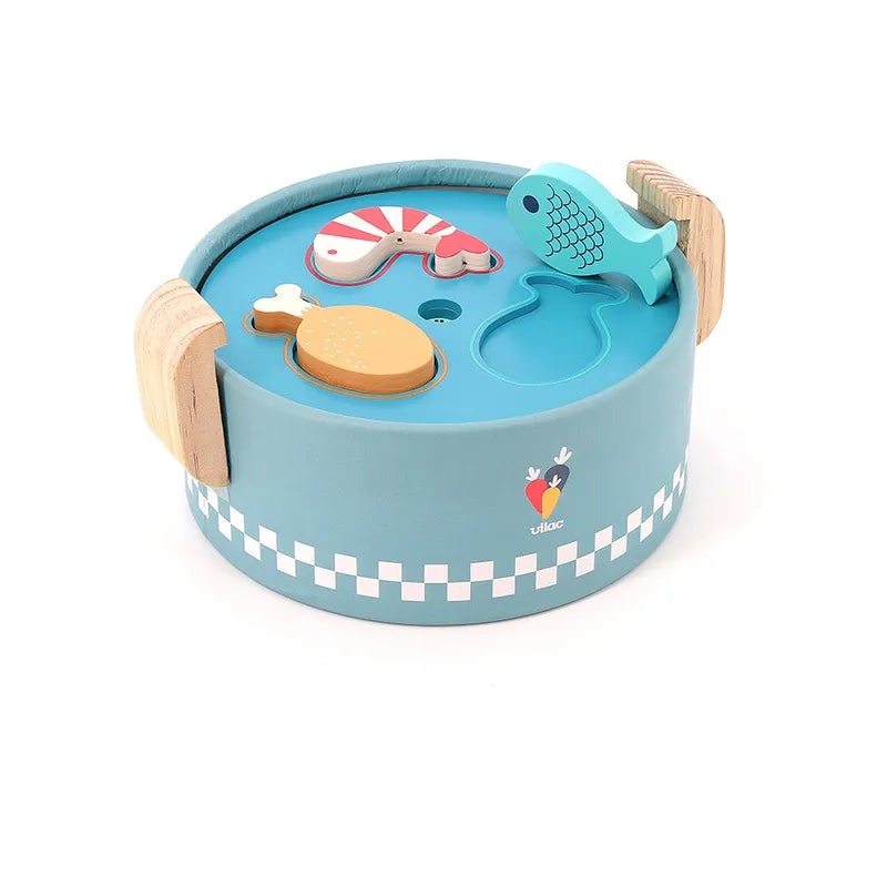 Introducing the Vilac Early Learning Cooking Pot: a round, blue wooden toy designed for children 18 months and older. It features handle grips on each side and has cut-out shapes on the top with matching pieces such as a fish, shrimp, and chicken drumstick. A checkered pattern decorates its sides, adding to its visual appeal.