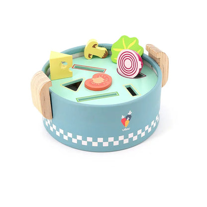 Introducing the Vilac Early Learning Cooking Pot: a vibrant and round wooden toy designed for children aged 18 months and older. It features a teal base bordered with white checks, and includes shaped cutouts along with corresponding wooden vegetable pieces like a tomato, onion, cheese, mushroom, and green leafy vegetable. Wooden handles on the sides make it easy to carry.