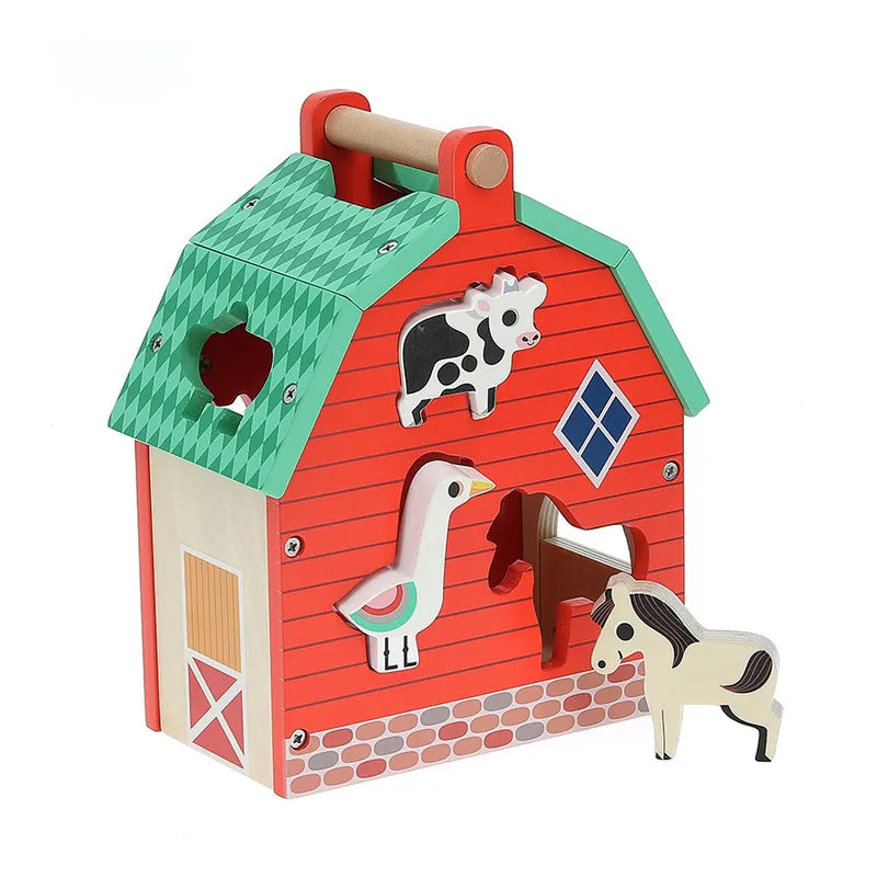 Vilac My Nice Farm Shape Sorter is a vibrant wooden toy barn, ideal for toddlers aged 2 years, featuring animal shapes and cutouts. The red barn with a green roof and handle has attached cow and goose figures. Beside the barn are a horse and another cow, designed to fit into specific cutout slots on the barn.