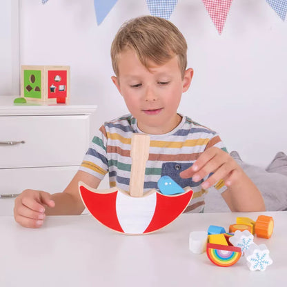 A 2-year-old boy playing with a Weather Balancing Game toy at a table.