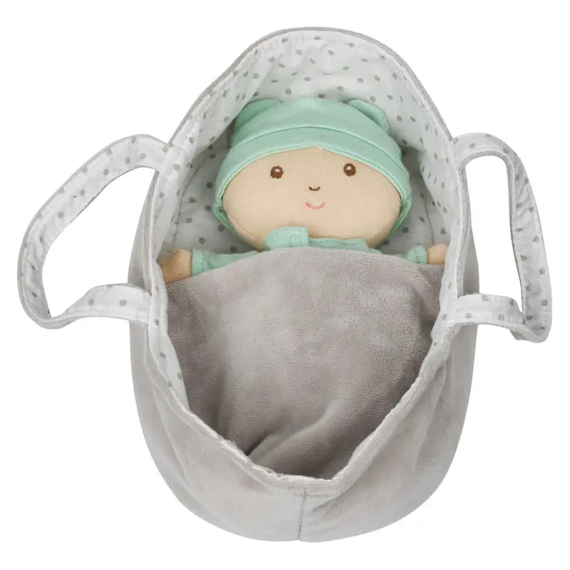 The Wilberry Baby Doll in Green Outfit comes with a soft doll in a mint green hat and outfit, tucked under a gray blanket inside a gray and white polka-dotted plush basket with two handles.