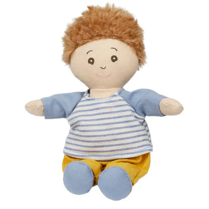 The Wilbery Baby Doll Boy Blue Outfit features soft light brown, fluffy hair, a blue and white striped shirt, yellow pants, and blue shoes. With a cheerful smile and outstretched arms, he's perfect for cuddles.