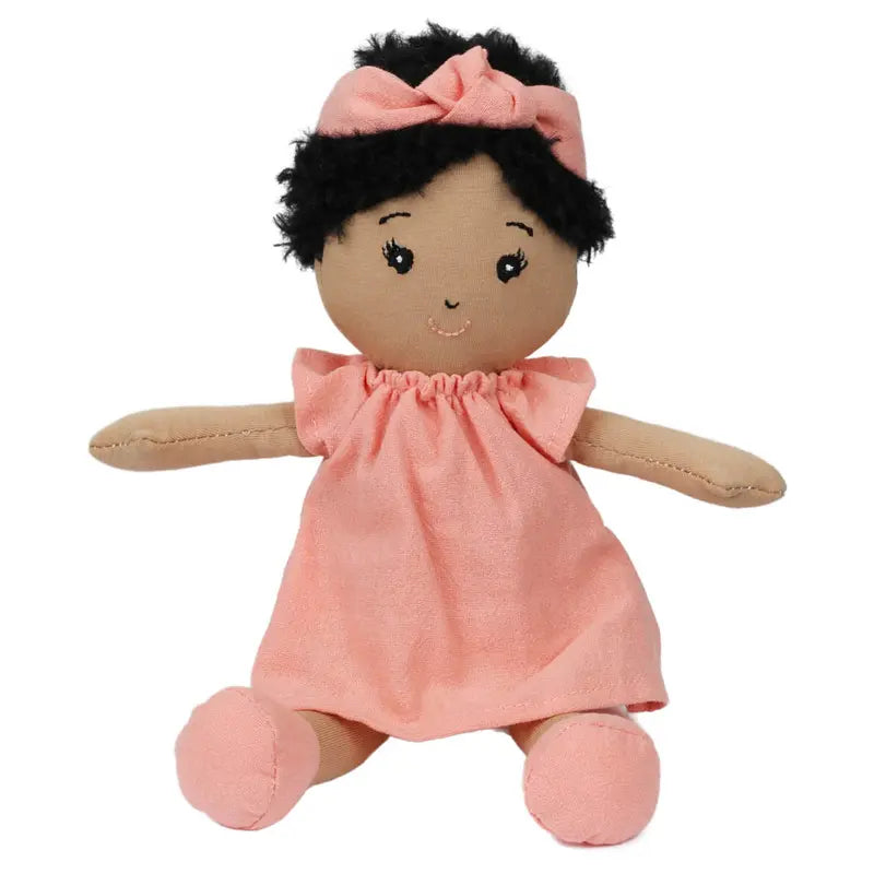 The Wilbery Baby Doll Girl Coral Outfit features soft black curly hair, a coral headband, and a matching dress. This charming doll sits with open arms and a sweet smile—perfect for brightening any room.