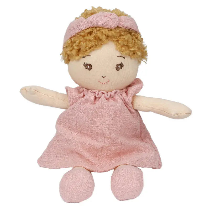 The Wilbery Baby Doll Girl Pink Outfit features soft fabric, curly blond hair, a pink dress with a matching headband, and simple stitched facial features with a sweet smile and outstretched arms.