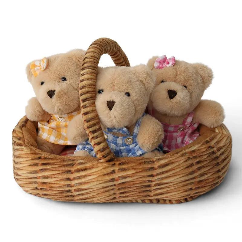 The Wilberry Teddy Bears’ Picnic Soft Toy Set features three plush teddy bears in blue, yellow, and pink checkered outfits with matching ribbon bows, all sitting together in a woven picnic basket, perfect for imaginative play.