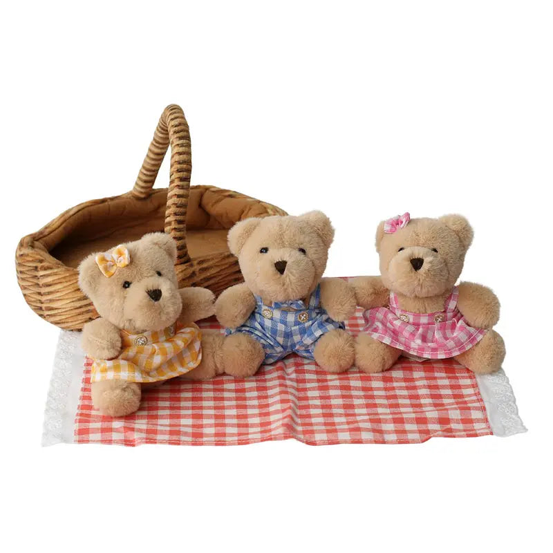 The Wilberry Teddy Bears’ Picnic Soft Toy Set features three plush teddy bears in yellow, blue, and pink checked outfits with matching bows, seated on a red-and-white picnic cloth with a plush picnic basket for imaginative play.