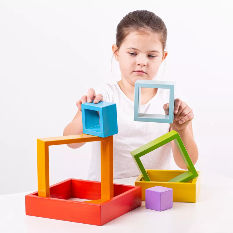 A little girl playing with Bigjigs Wooden Stacking Squares and a mirror.