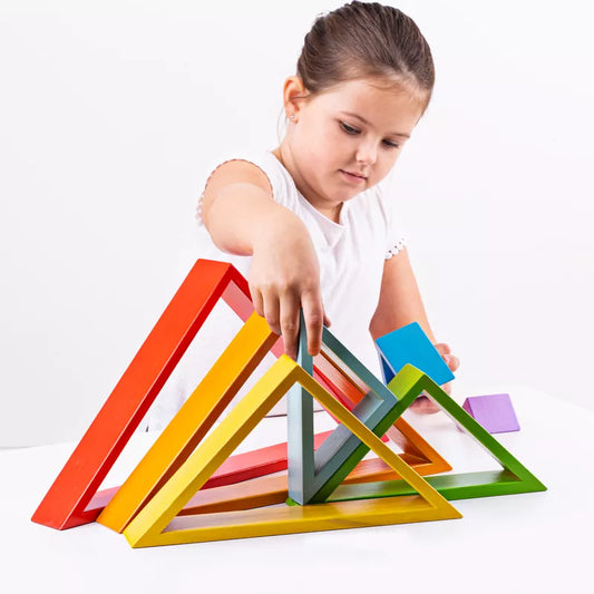 A little girl playing with a stack of Bigjigs Wooden Stacking Triangles.