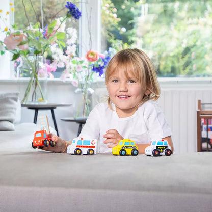 A little girl sitting at a table with the New Classic Toys Wooden Vehicles set of 4.