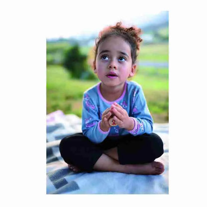 A little girl sits on a blanket and looks up at the Yogi Dice.