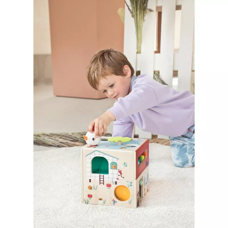 A little boy playing with a Lilliputiens Wooden Activity Cube Farm.