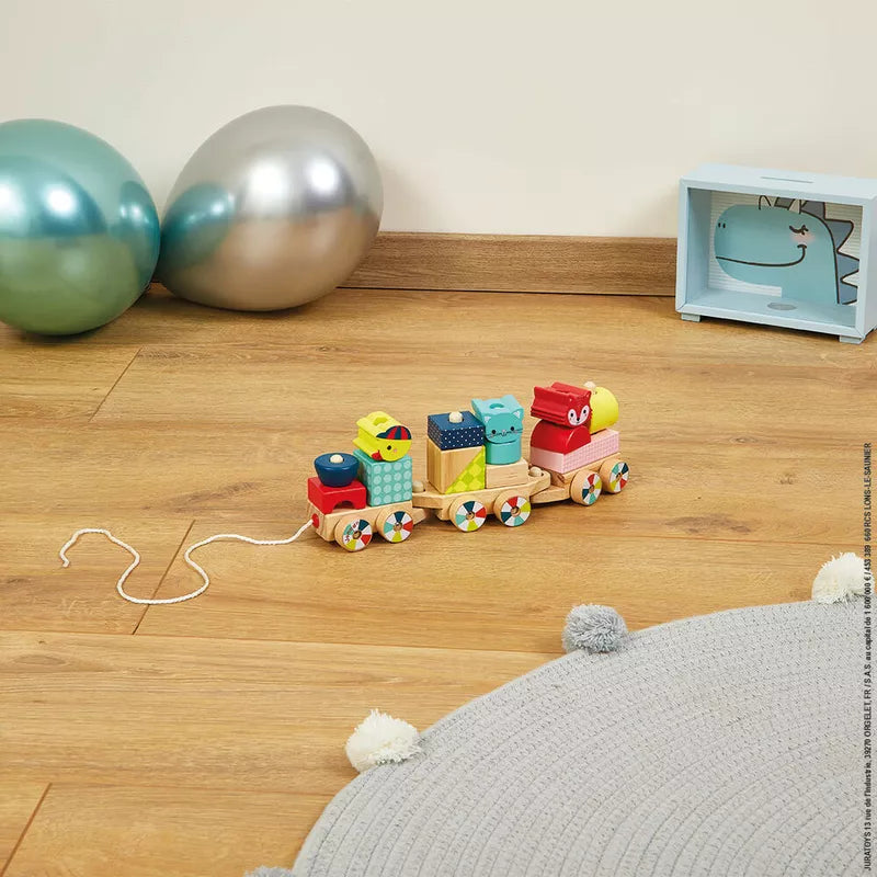 A Janod Baby Forest Train is on the floor next to balloons.
