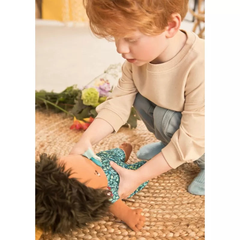 A young boy playing with a Lilliputiens Babydoll Sasha on the floor.