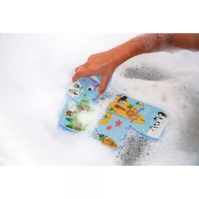 A child's hand in a bathtub playing with Janod Bath Explorers Map foam.