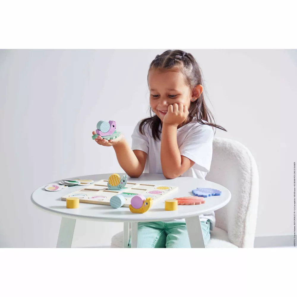 A little girl sitting at a Janod Double Entry Table Snails with toys.