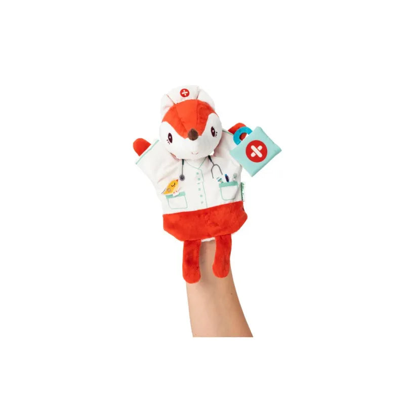 The Lilliputiens Alice Doctor Handpuppet, a plush fox dressed as a doctor, features a white coat with medical equipment printed on it. Perfect for imaginative play, this puppet has red and white coloration and is machine washable. Held up by a hand entering from the bottom of the frame.