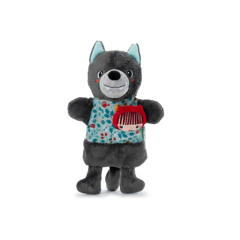 A soft plush toy shaped like a friendly gray wolf with blue ears and a patterned front. The wolf has a smiling face, and the front features a print of a small girl with red hair, perfect for imaginative and creative play. The toy, akin to the Lilliputiens Louis Wolf Handpuppet, stands upright.