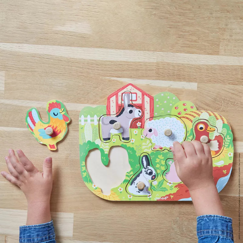 A child's hands playing with the Janod Happy Farm Puzzle.