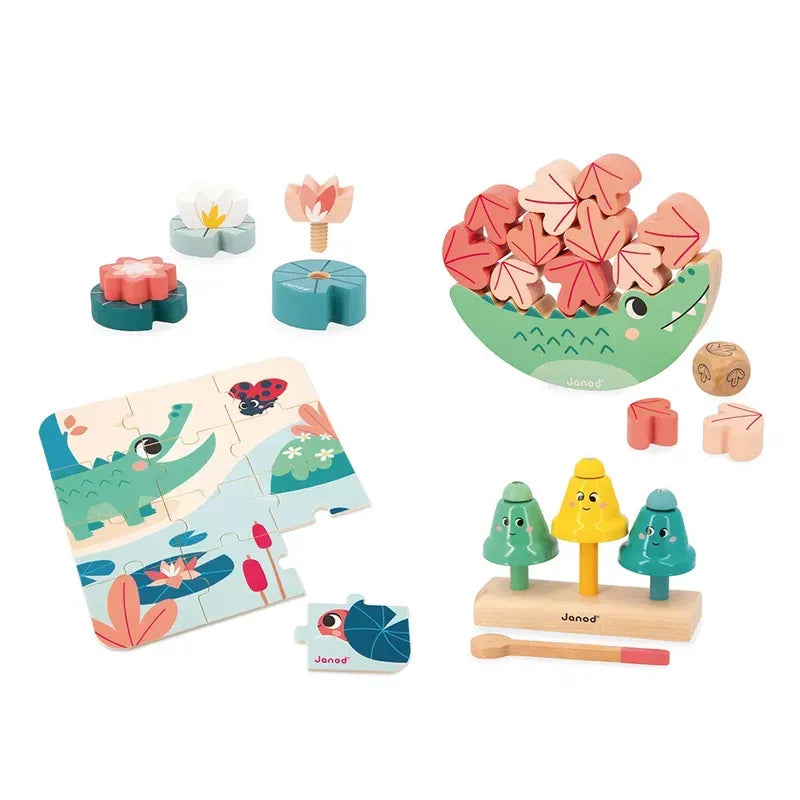 A colorful assortment of wooden toys and puzzles perfect for early-years development. The set includes a flower stacking toy, a hedgehog balancing toy with pink and red pieces, a crocodile-themed jigsaw puzzle, a wooden rolling die, and a wooden toy with three tree-shaped figures on pegs called the Janod Box of Toys 24 Months.