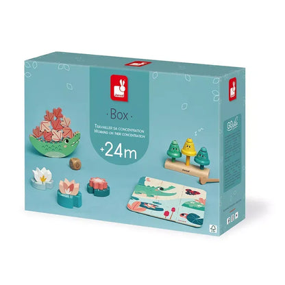 A Janod Box of Toys 24 Months with a blue background displaying a set of wooden sensory toys aimed at improving concentration in children aged 24 months and older. The toys include peg dolls, stacking rings, and a puzzle. The packaging features a red logo and multilingual text, perfect for early-years development.