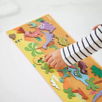 A child's hand interacting with Janod Magneti'stories Dinosaurs on a light background.