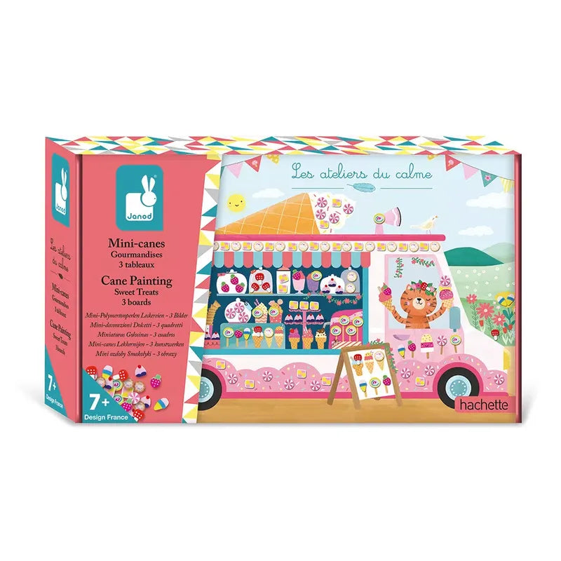 Introducing the Janod Cane Painting Sweet Treats craft kit box titled "Les Ateliers du Calme." This vibrant package features a beautifully decorated pink van with adorable animals selling ice cream. The creative kit includes all the materials needed for making charming mini-cane sweet treats. Perfect for children aged 7 to 12, this delightful decorating activity is brought to you by Janod and Hachette.