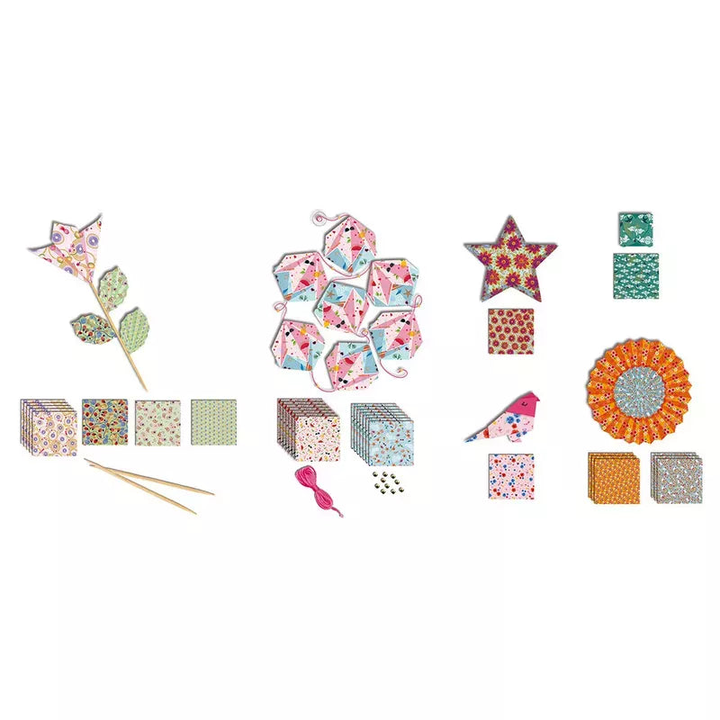 Janod Origami Delightful Decoration kit materials and small decorative items arranged neatly against a white background, featuring patterned papers for origami, decorative birds, a pair of knitting needles, and a beadwork flower