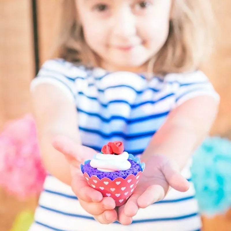 A little girl holding a Sentosphere Patarev Clay Cupcakes toy in her hands.
